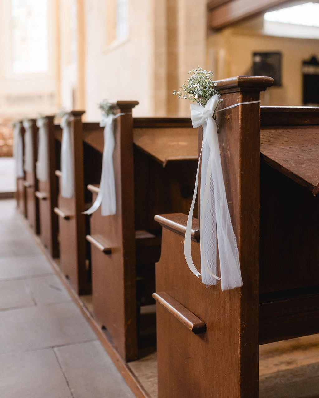 Festliche Schleifen aus Tüll als Dekoration für die Kirchenbank