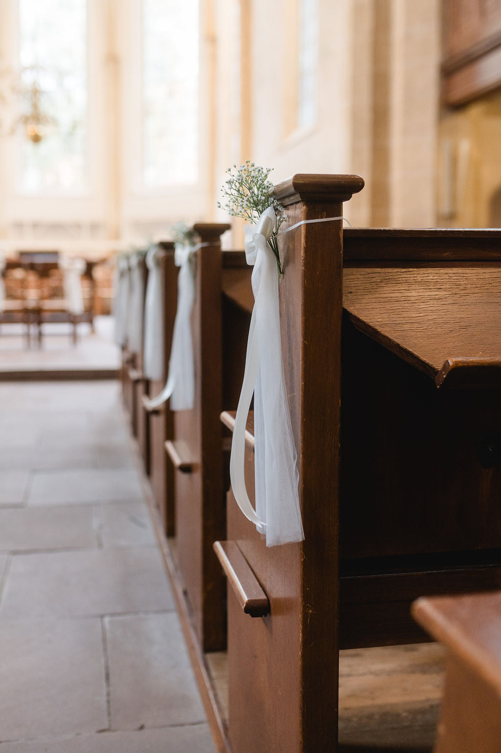 Stimmungsvolle Kirchbankdeko mit weißen Schleifen zur Hochzeit