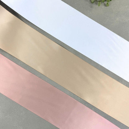 Grabschleifenbänder in 10 cm Breite in den Farben Weiß, Champagner und Altrosa auf grauem Hintergrund