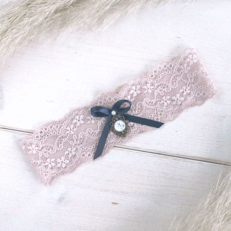 Strumpfband aus zarter altrosa Spitze mit einem dunkelblauen Detail.